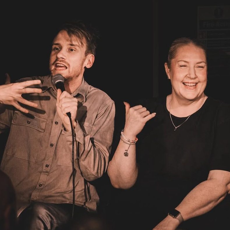 A comedian performing beside a guest judge